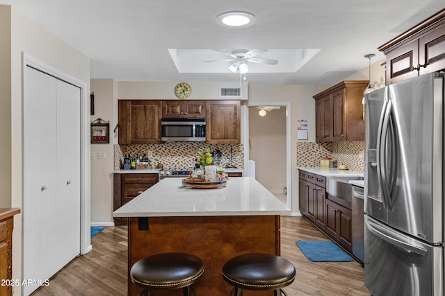 kitchen featuring light wood finished floors, visible vents, ceiling fan, a skylight, and stainless steel appliances