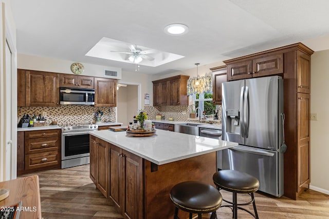 kitchen featuring visible vents, ceiling fan, light countertops, a tray ceiling, and appliances with stainless steel finishes