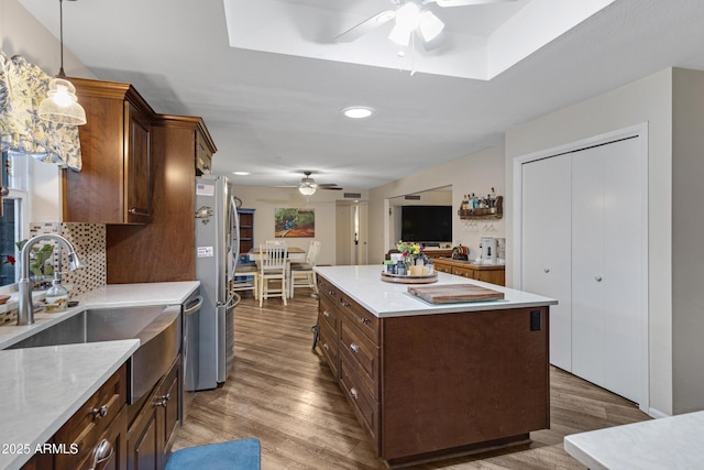 kitchen with wood finished floors, a ceiling fan, a kitchen island, a sink, and appliances with stainless steel finishes