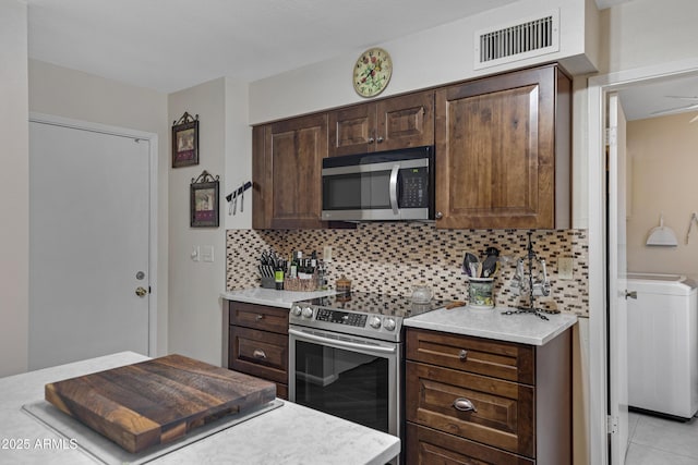 kitchen featuring visible vents, washer / dryer, light countertops, appliances with stainless steel finishes, and backsplash