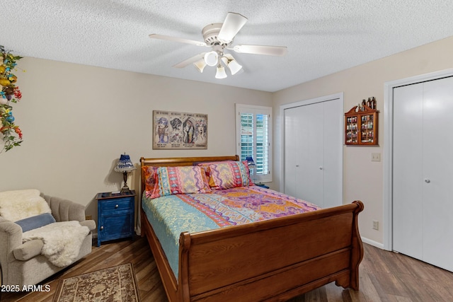 bedroom featuring ceiling fan, multiple closets, a textured ceiling, and wood finished floors