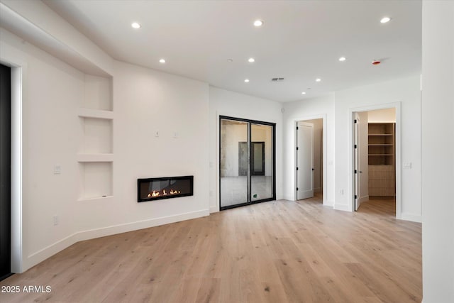 6202 E Larkspur Dr, Scottsdale, AZ 85254 - unfurnished living room featuring baseboards, recessed lighting, light wood-style floors, a glass covered fireplace, and built in shelves