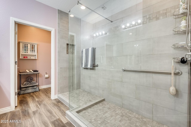 full bathroom featuring a walk in shower, wood finished floors, visible vents, and baseboards