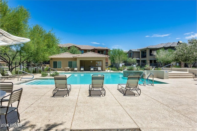 community pool with a patio and fence