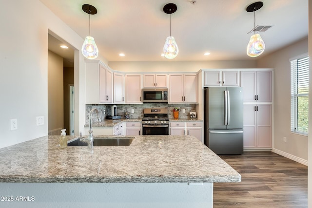 kitchen featuring visible vents, decorative backsplash, stainless steel appliances, white cabinetry, and a sink