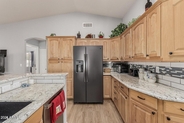 kitchen with lofted ceiling, backsplash, light stone countertops, appliances with stainless steel finishes, and light hardwood / wood-style floors