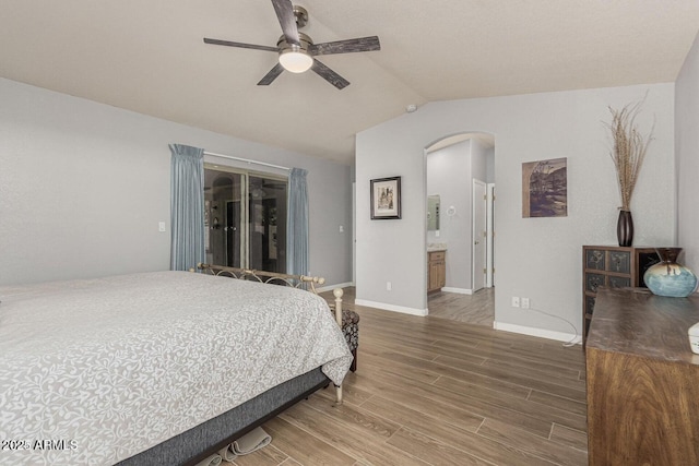 bedroom with hardwood / wood-style floors, vaulted ceiling, ceiling fan, access to exterior, and connected bathroom