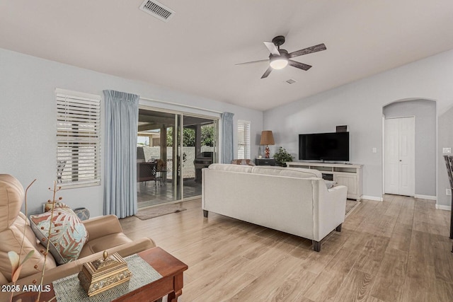 living room with ceiling fan, light hardwood / wood-style floors, and vaulted ceiling