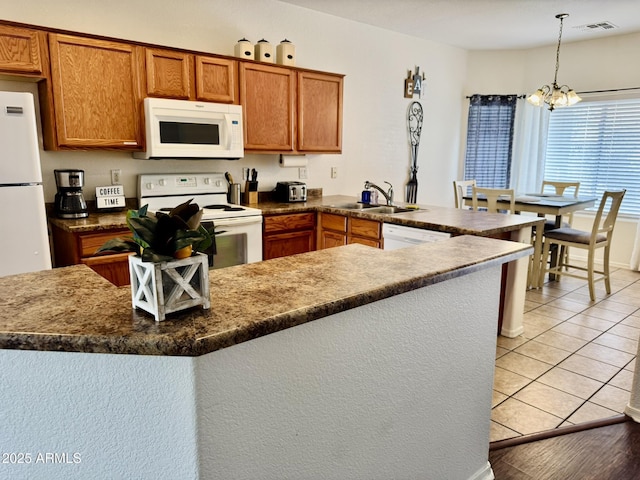 12371 W Hadley St, Avondale, AZ 85323 - kitchen with white appliances, a peninsula, light tile patterned flooring, a sink, and brown cabinets