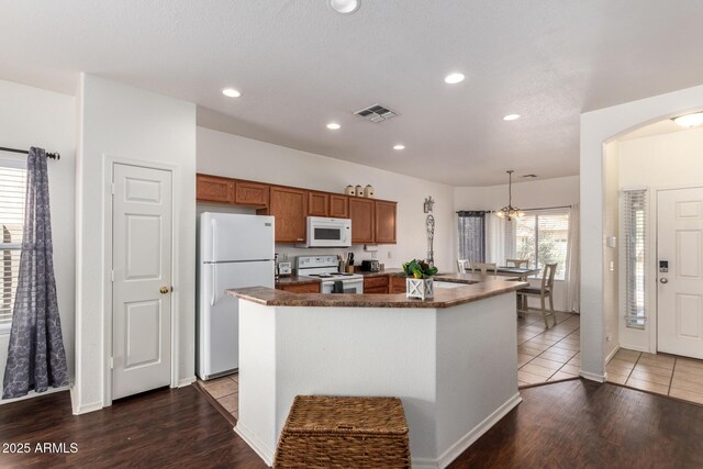 12371 W Hadley St, Avondale, AZ 85323 - kitchen featuring white appliances, arched walkways, visible vents, dark countertops, and brown cabinets