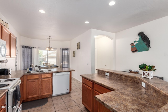 12371 W Hadley St, Avondale, AZ 85323 - kitchen featuring arched walkways, a sink, dark countertops, white appliances, and a peninsula