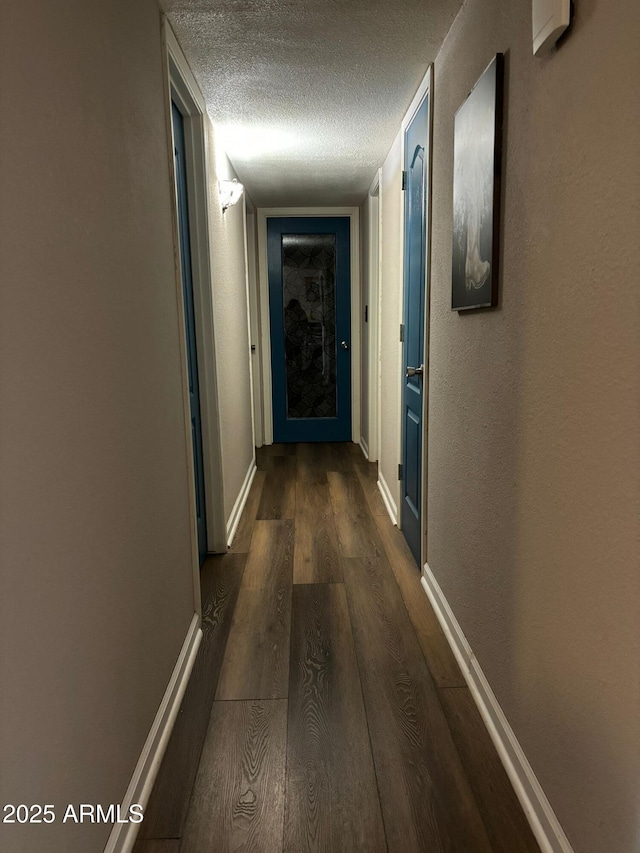 hallway with a textured ceiling and dark hardwood / wood-style flooring