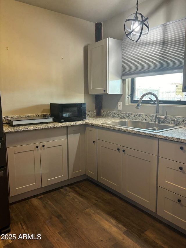 kitchen featuring dark wood-type flooring, sink, hanging light fixtures, and white cabinets