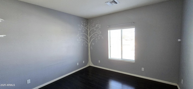 empty room with dark wood-style flooring, visible vents, and baseboards