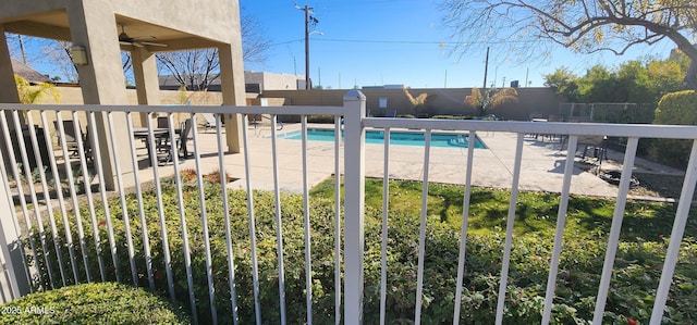 pool with a patio area, fence, and ceiling fan