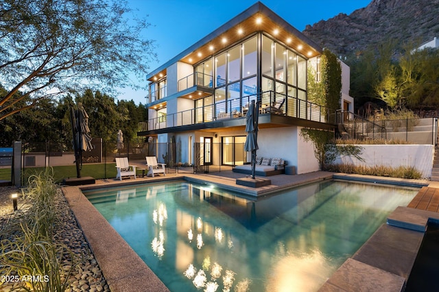 back of house featuring a fenced in pool, a patio area, and a balcony