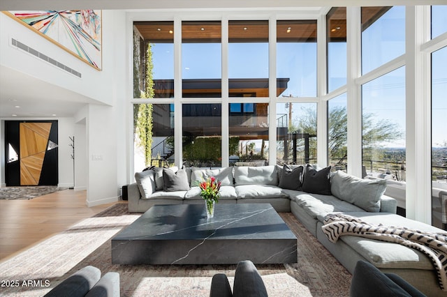 living room with hardwood / wood-style floors, a towering ceiling, and a wall of windows