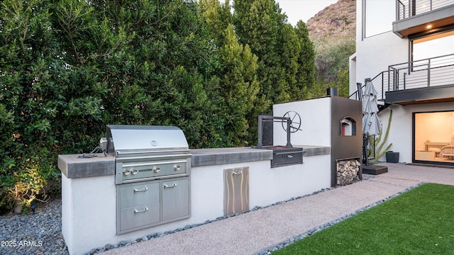 view of patio / terrace featuring grilling area, a balcony, and exterior kitchen