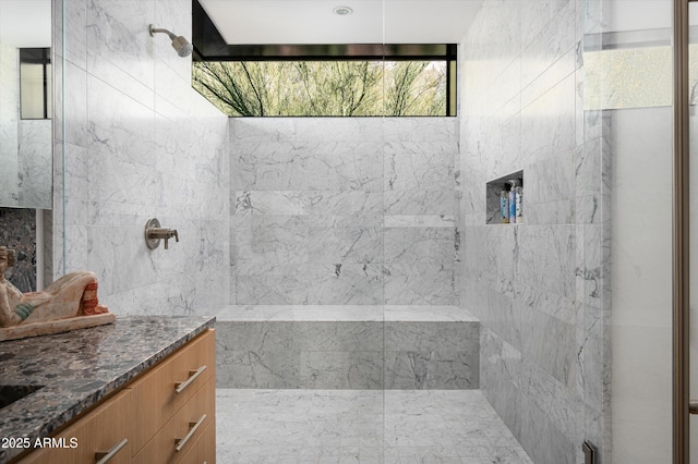 bathroom featuring tiled shower and vanity