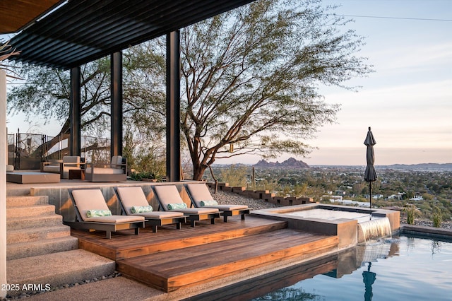 deck at dusk with a jacuzzi and pool water feature