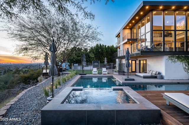 pool at dusk with an in ground hot tub and an outdoor fire pit