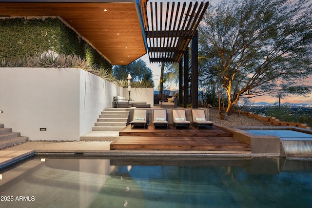 pool at dusk featuring a hot tub, a pergola, and a deck