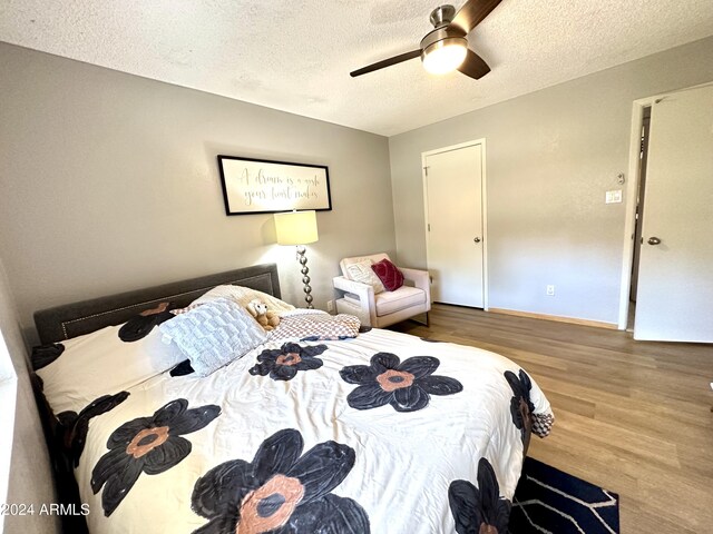 bedroom with a textured ceiling, wood finished floors, baseboards, and ceiling fan