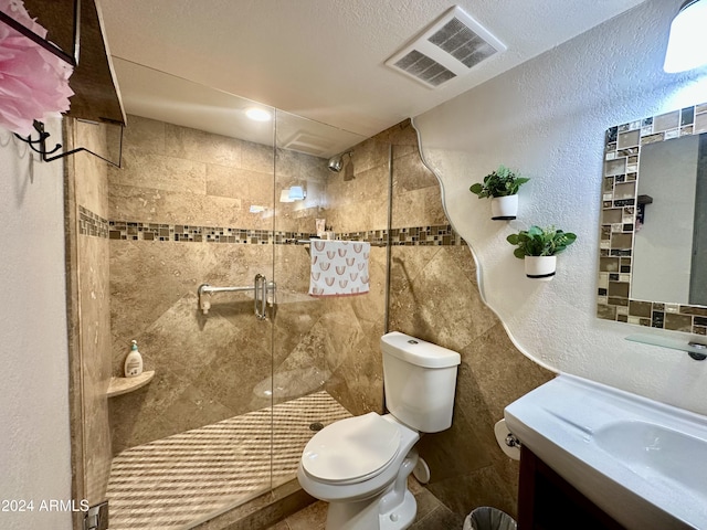 full bathroom featuring toilet, a stall shower, visible vents, a textured wall, and vanity