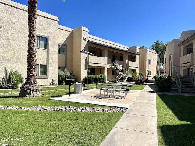 view of property's community featuring a patio area, stairway, and a lawn