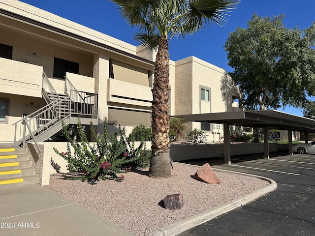 view of building exterior with stairs and covered parking
