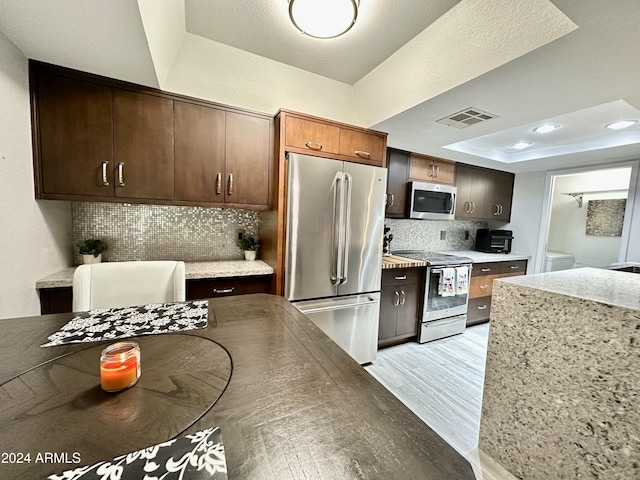kitchen with light wood-style flooring, visible vents, backsplash, a raised ceiling, and appliances with stainless steel finishes