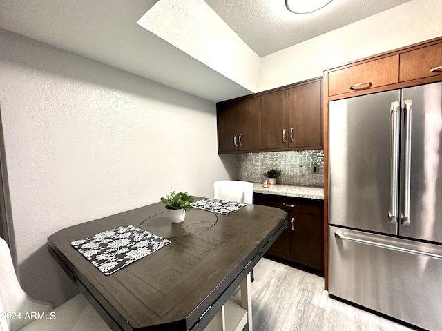 kitchen featuring freestanding refrigerator, dark brown cabinets, backsplash, and light wood finished floors