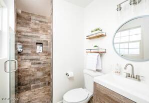 bathroom featuring toilet, walk in shower, and vanity