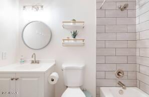 full bathroom featuring vanity, tiled shower / bath combo, and toilet