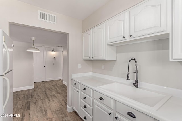 1650 N 87th Ter Unit 25A, Scottsdale, AZ 85257 - kitchen with freestanding refrigerator, white cabinets, light wood-style floors, light countertops, and hanging light fixtures