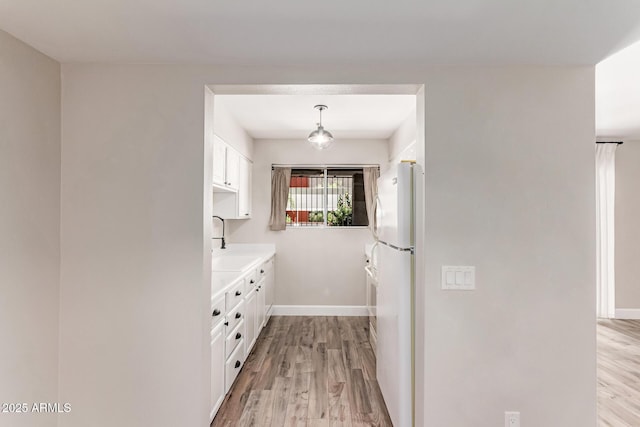 1650 N 87th Ter Unit 25A, Scottsdale, AZ 85257 - kitchen with light wood-style flooring, white cabinets, light countertops, freestanding refrigerator, and pendant lighting