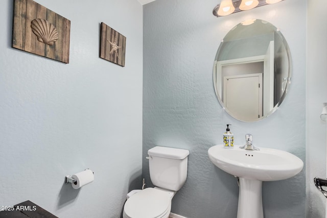 bathroom with toilet and a textured wall