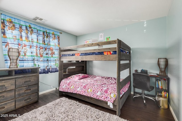 bedroom with baseboards, visible vents, and wood finished floors