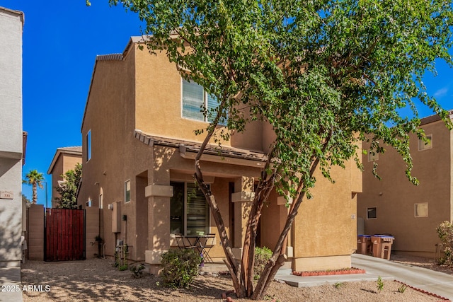 adobe home featuring a gate, fence, and stucco siding