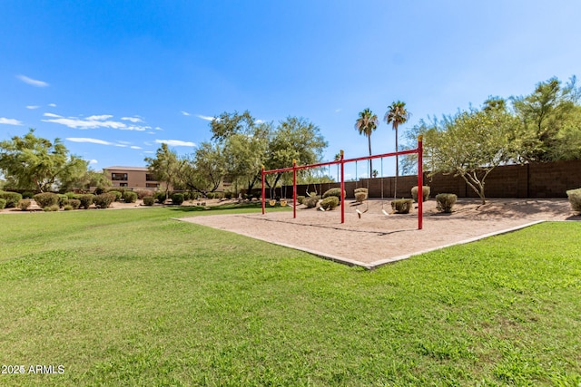 community play area featuring a yard and fence