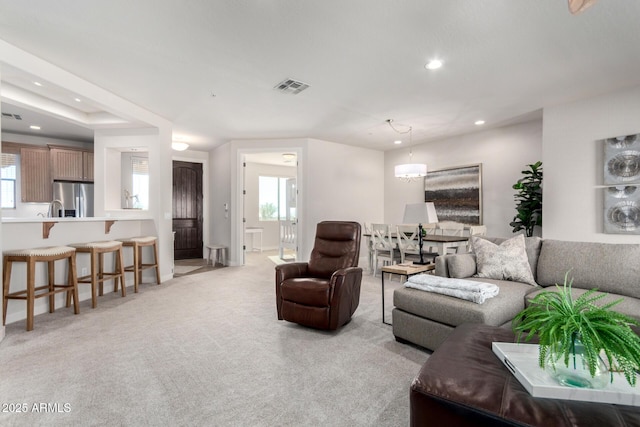 carpeted living room featuring a notable chandelier