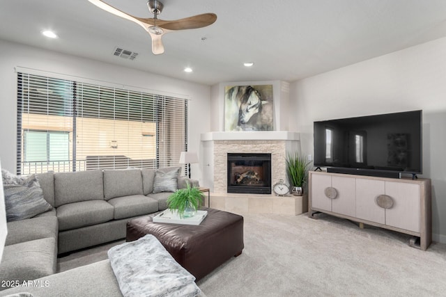 living room with ceiling fan, light carpet, and a fireplace