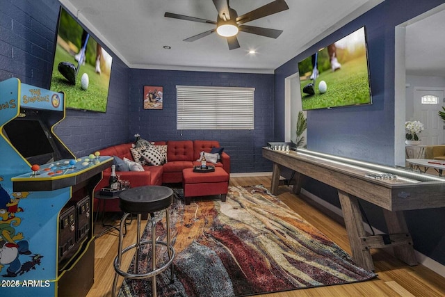 playroom featuring hardwood / wood-style floors, ceiling fan, and brick wall