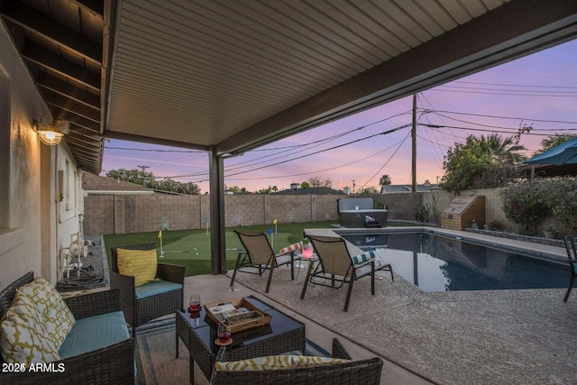 patio terrace at dusk with an outdoor living space and a fenced in pool