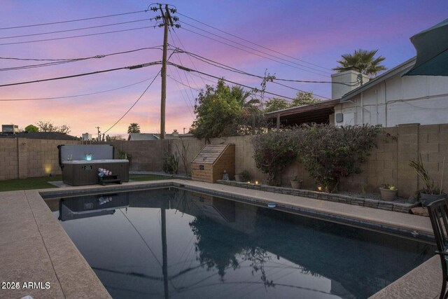 pool at dusk with a hot tub