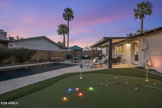 pool at dusk featuring a patio area