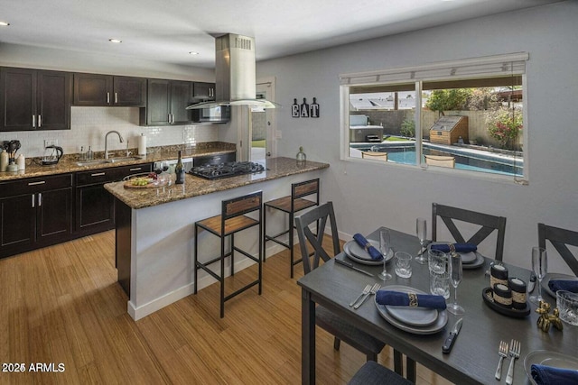 kitchen featuring island range hood, gas stovetop, light wood-type flooring, and sink