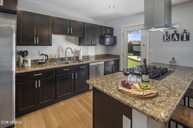 kitchen with a breakfast bar, black appliances, sink, light hardwood / wood-style floors, and extractor fan