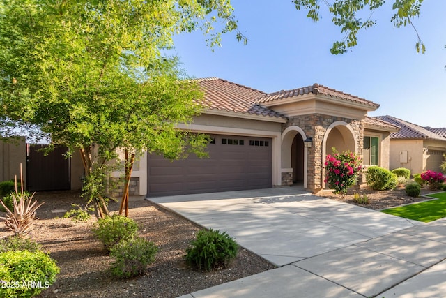 20783 W Pasadena Ave, Buckeye, AZ 85396 - mediterranean / spanish house with stone siding, an attached garage, stucco siding, a tile roof, and driveway