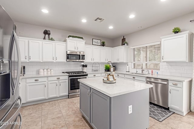kitchen with visible vents, a sink, white cabinets, appliances with stainless steel finishes, and a center island